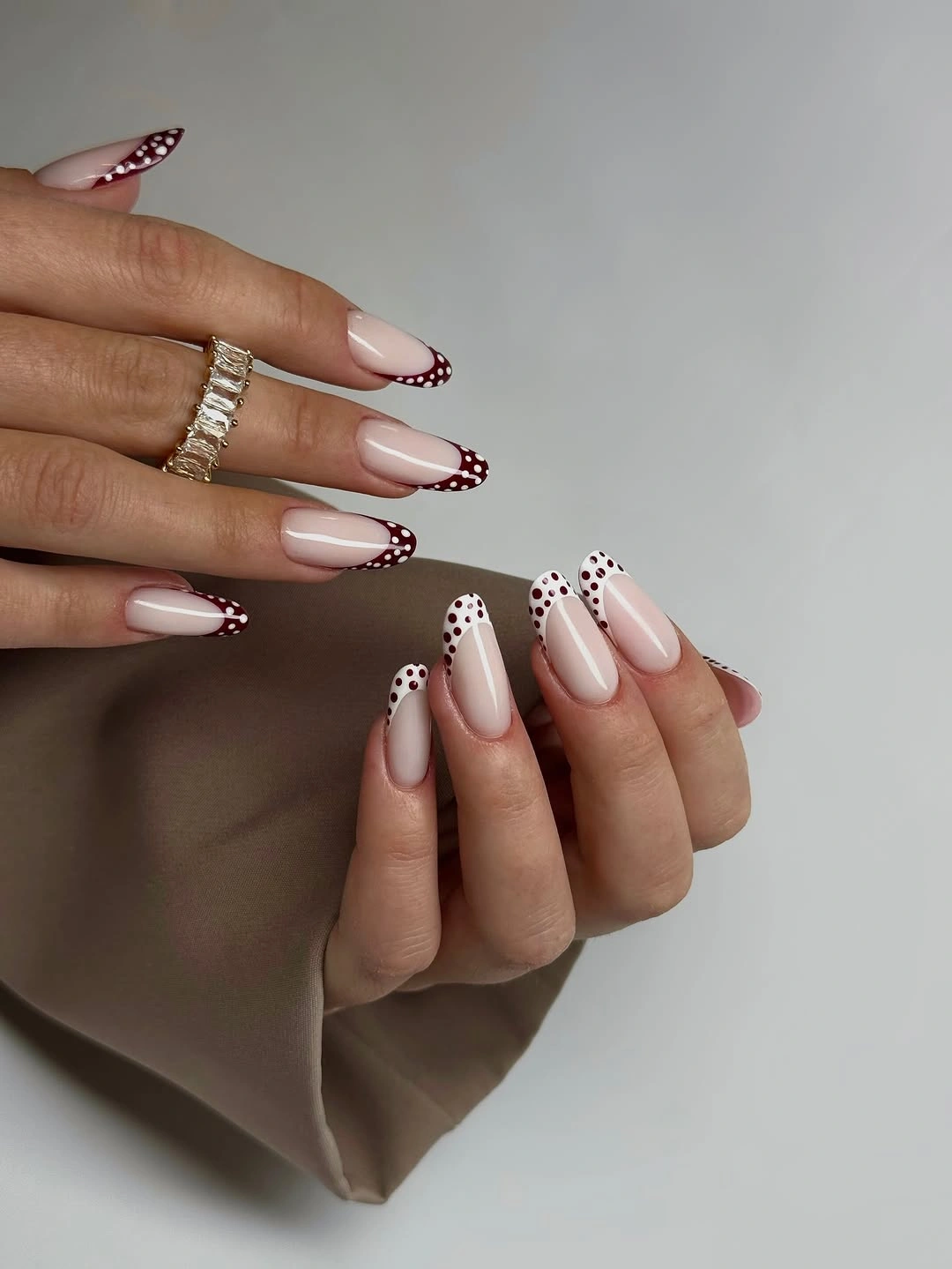 Nude almond nails with burgundy dotted French tips