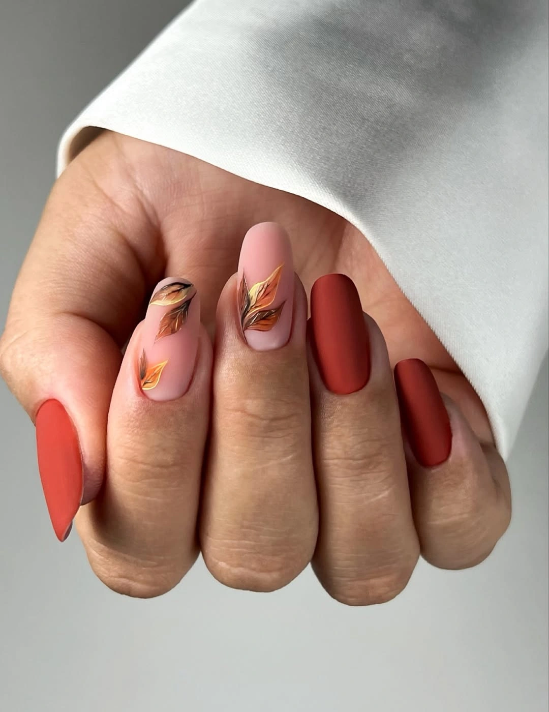Terracotta almond nails with pale leaf accents
