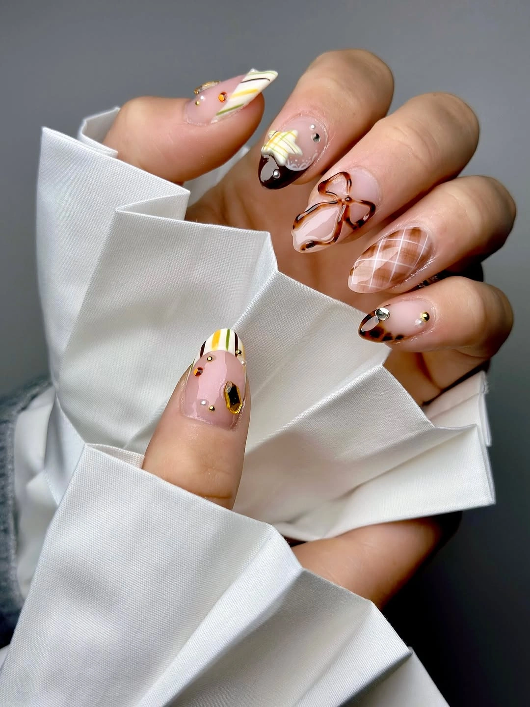 Long almond nails with brown abstract lines and a checked accent