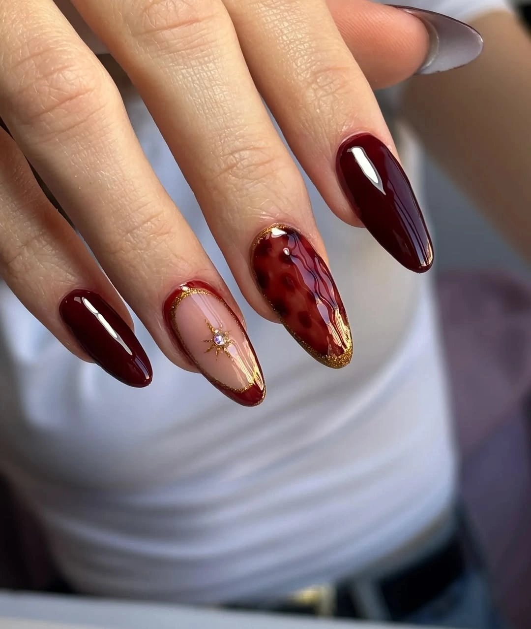 Medium burgundy nails with amber patterned and gold accent detail