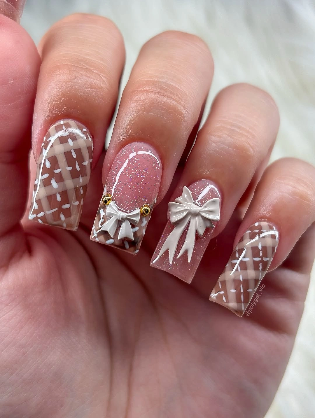 Short square pink glitter nails with plaid and silver bow accents