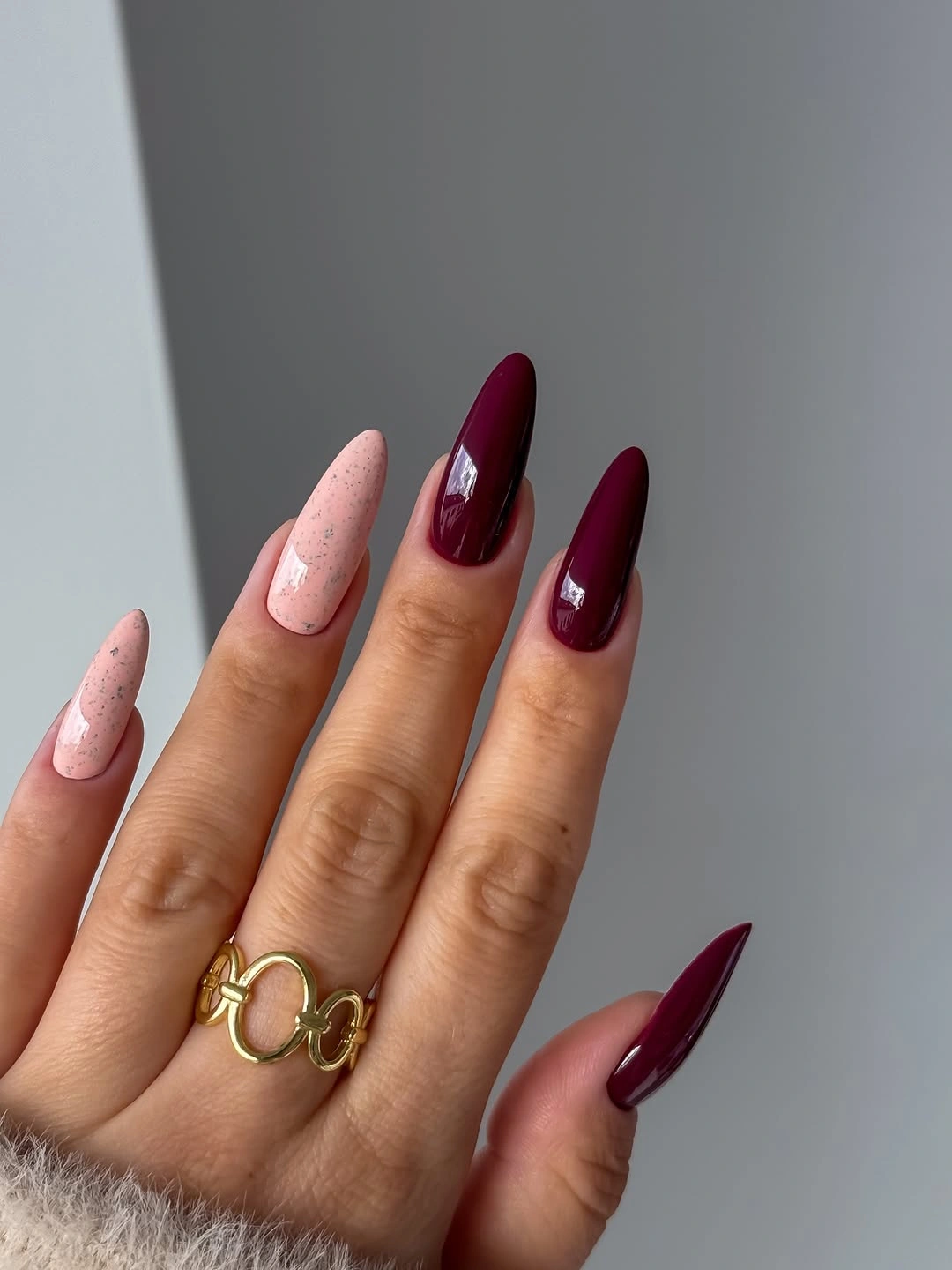 Deep wine stiletto nails with speckled blush accents