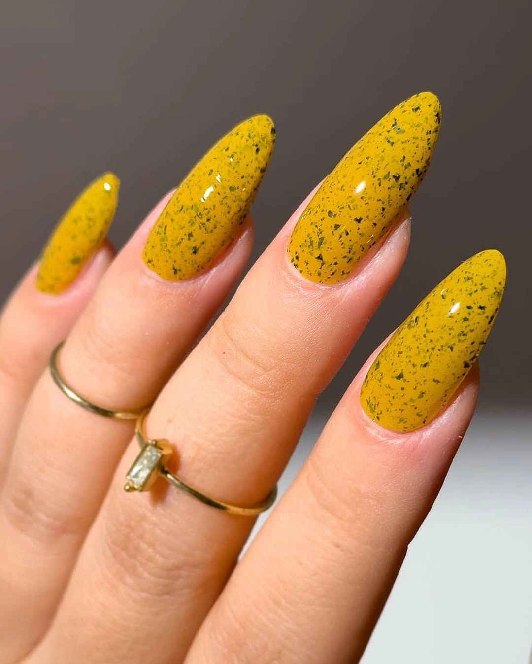 Long almond mustard nails with fine dark speckles