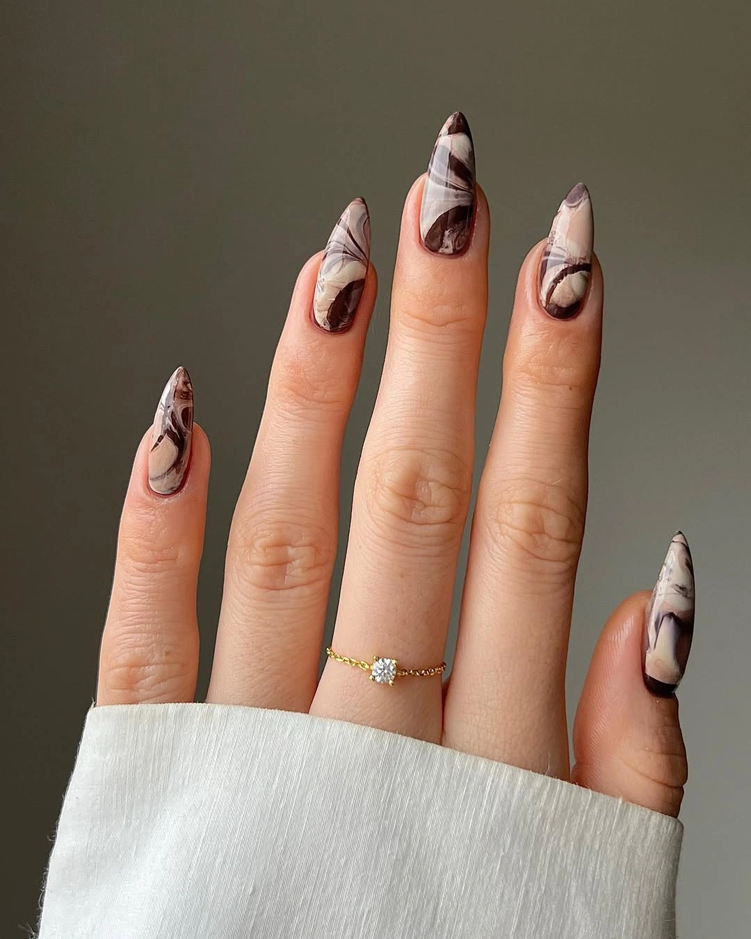 Long almond cream nails with brown and black abstract swirls
