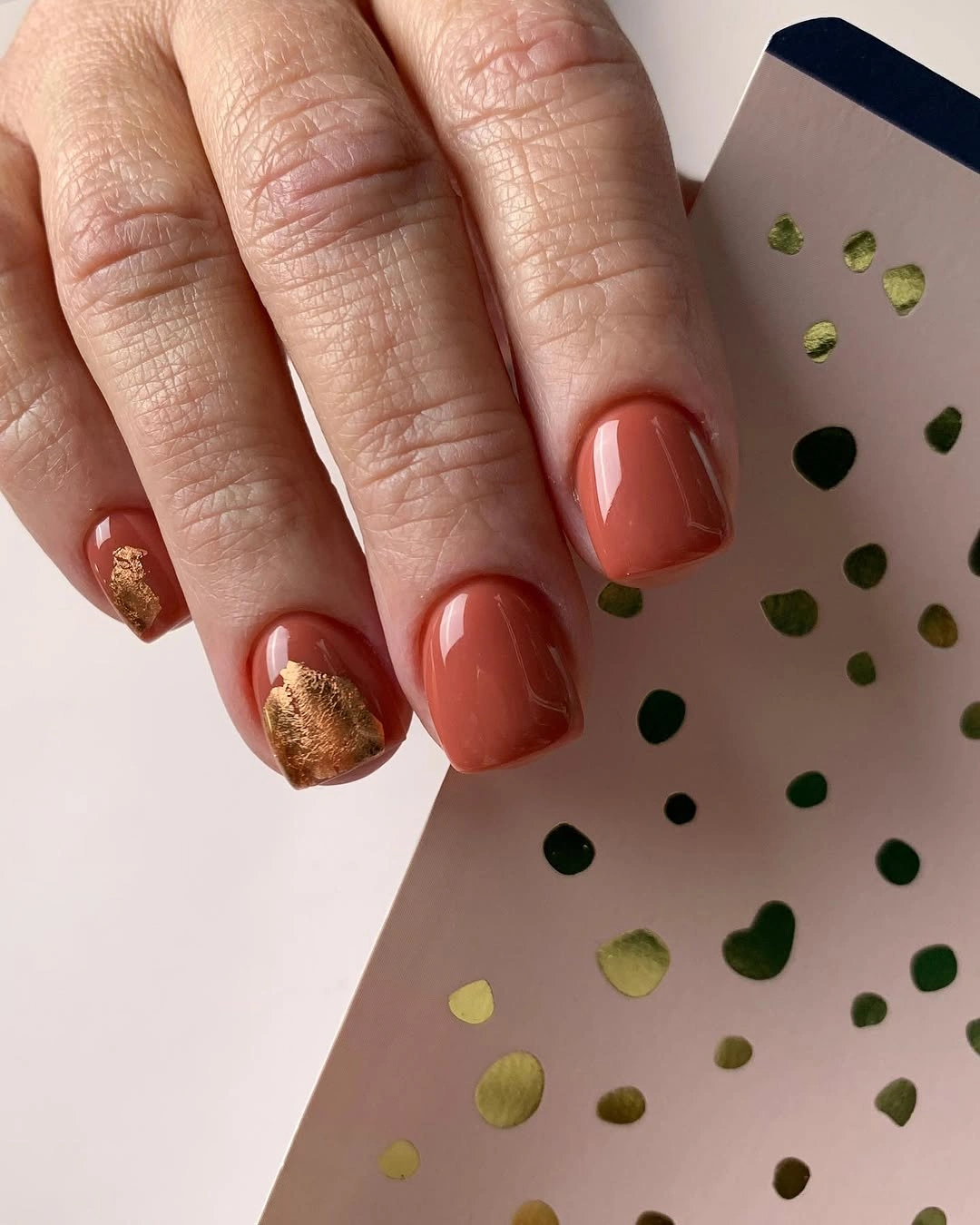 Short terracotta square nails with small gold accents