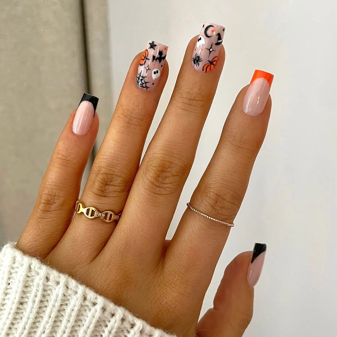 Long almond nude nails with black tips and tiny playful orange details