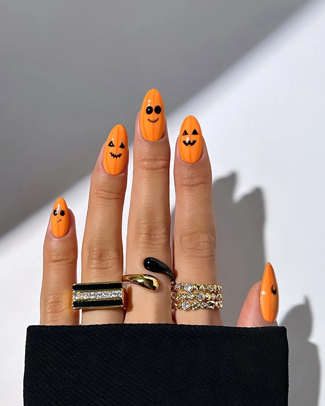 Long orange almond nails with small black pumpkin face designs