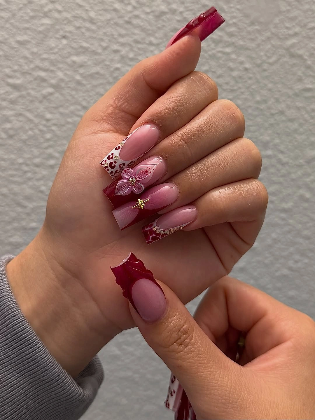 Long almond pink nails with raised burgundy flowers and white accents
