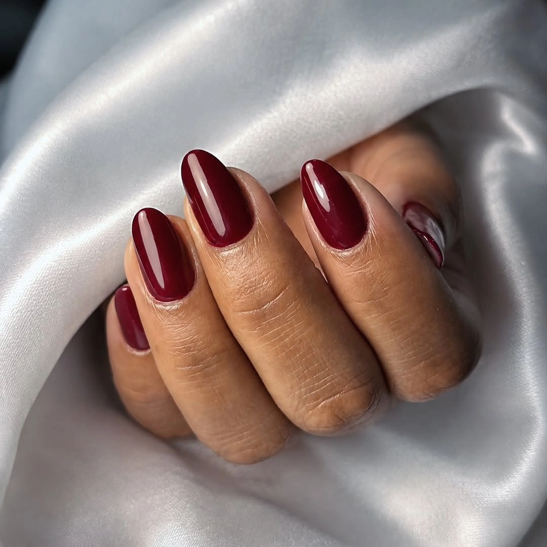 Glossy deep burgundy nails on a rounded shape