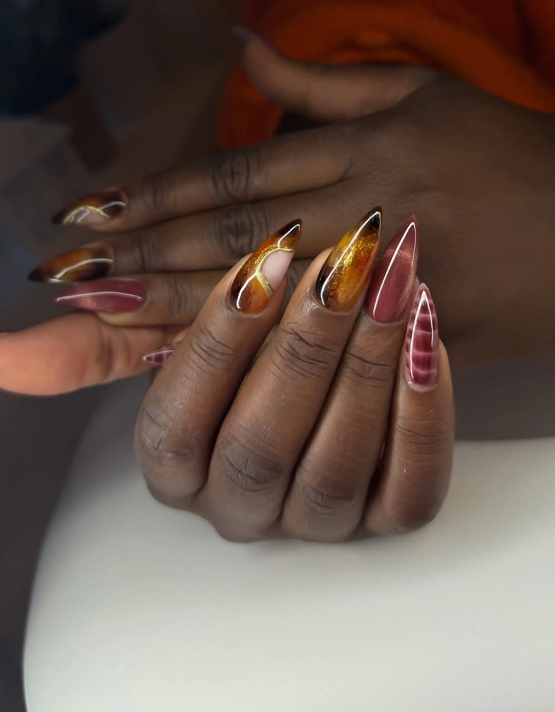 long pointed nails with layered brown and red accents