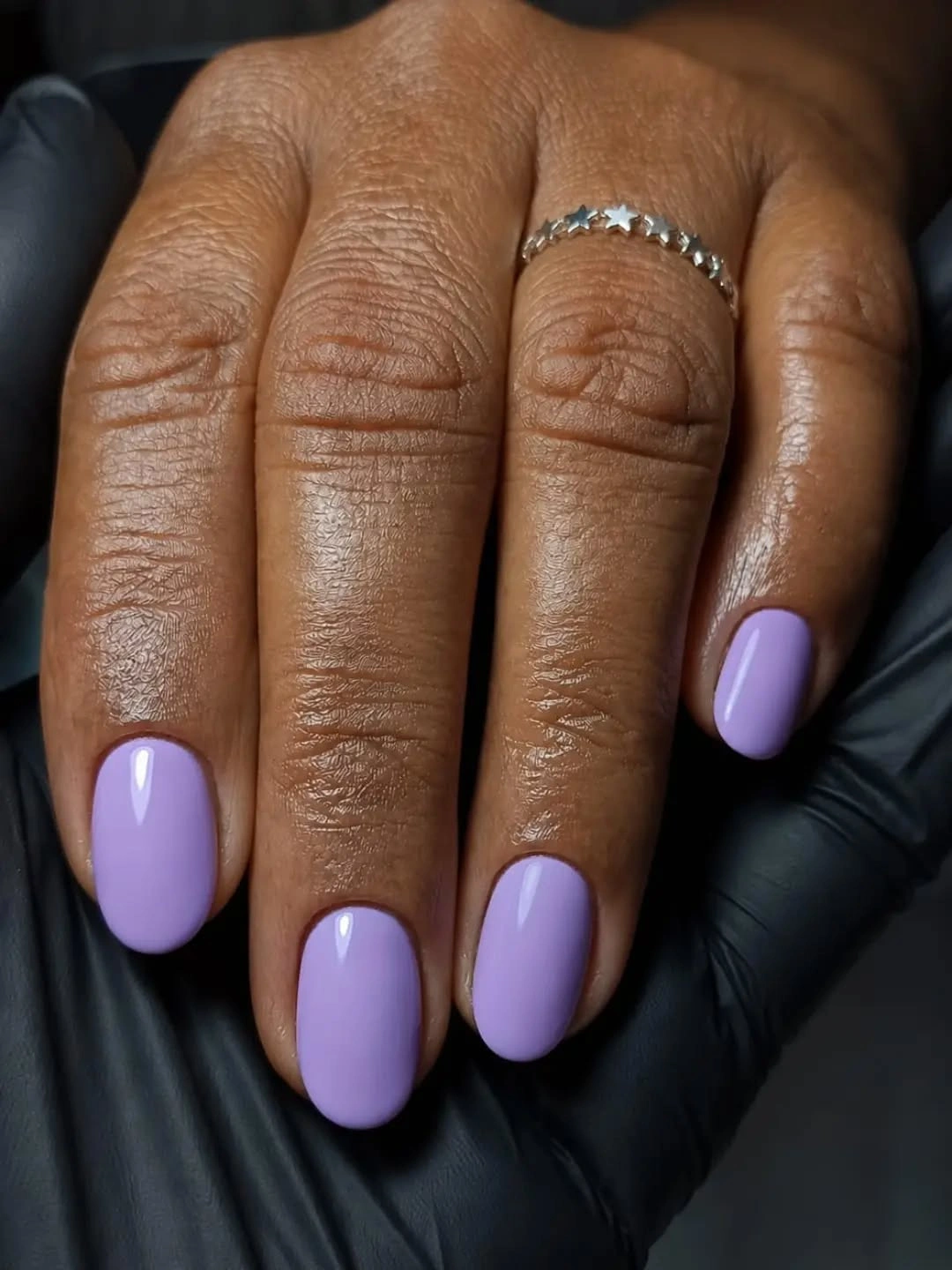 Short oval nails painted in a glossy solid lavender shade