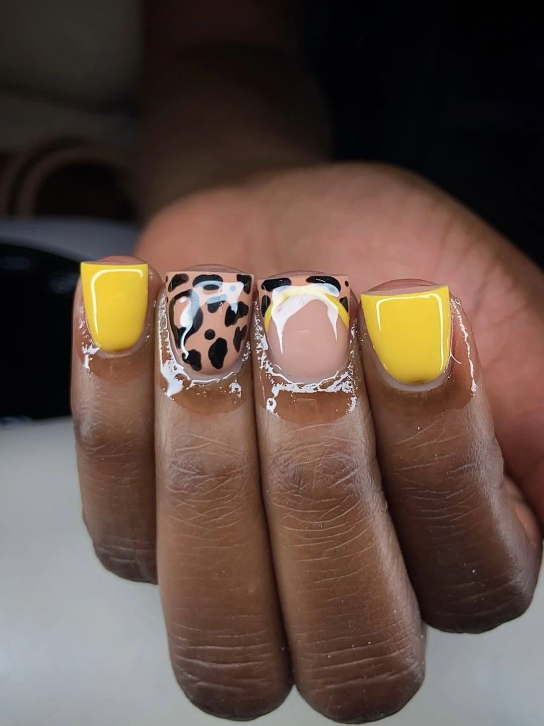 Short square yellow nails with pink blocks and a black spotted accent nail