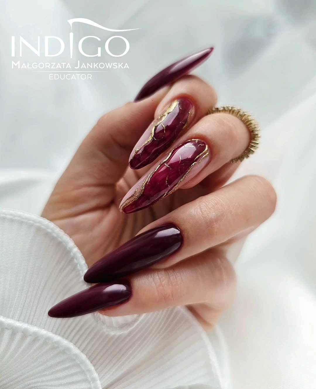 Long burgundy stiletto nails with marbled panels and gold lines