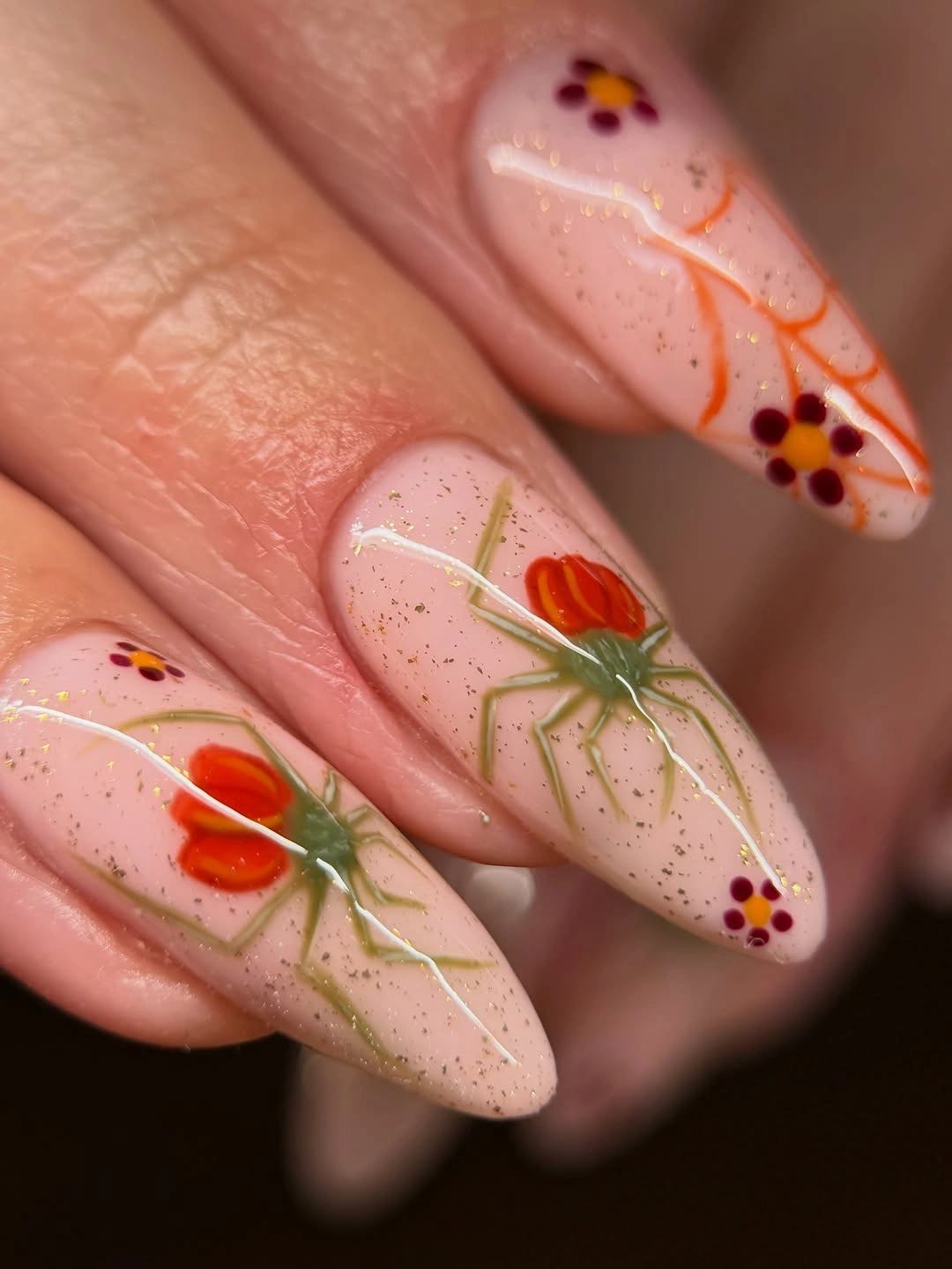 Sheer almond nails with orange flowers green vines and dots