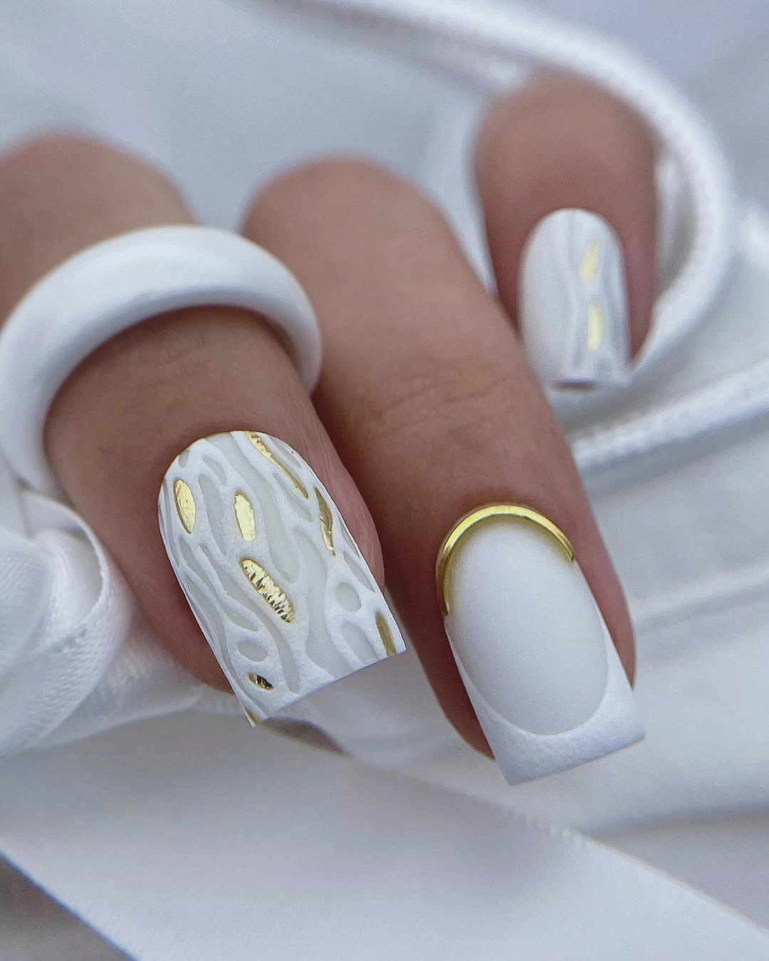 Long matte white square nails with pale raised accents and gold details