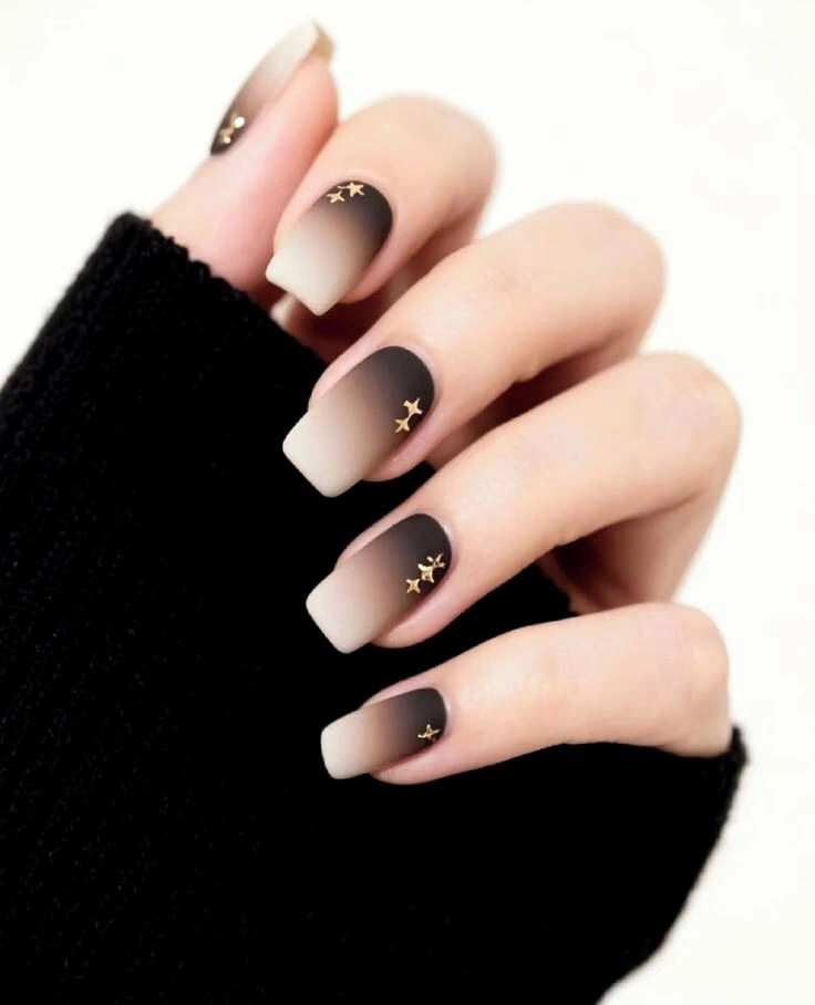Medium square nails fading from nude to black with tiny gold stars