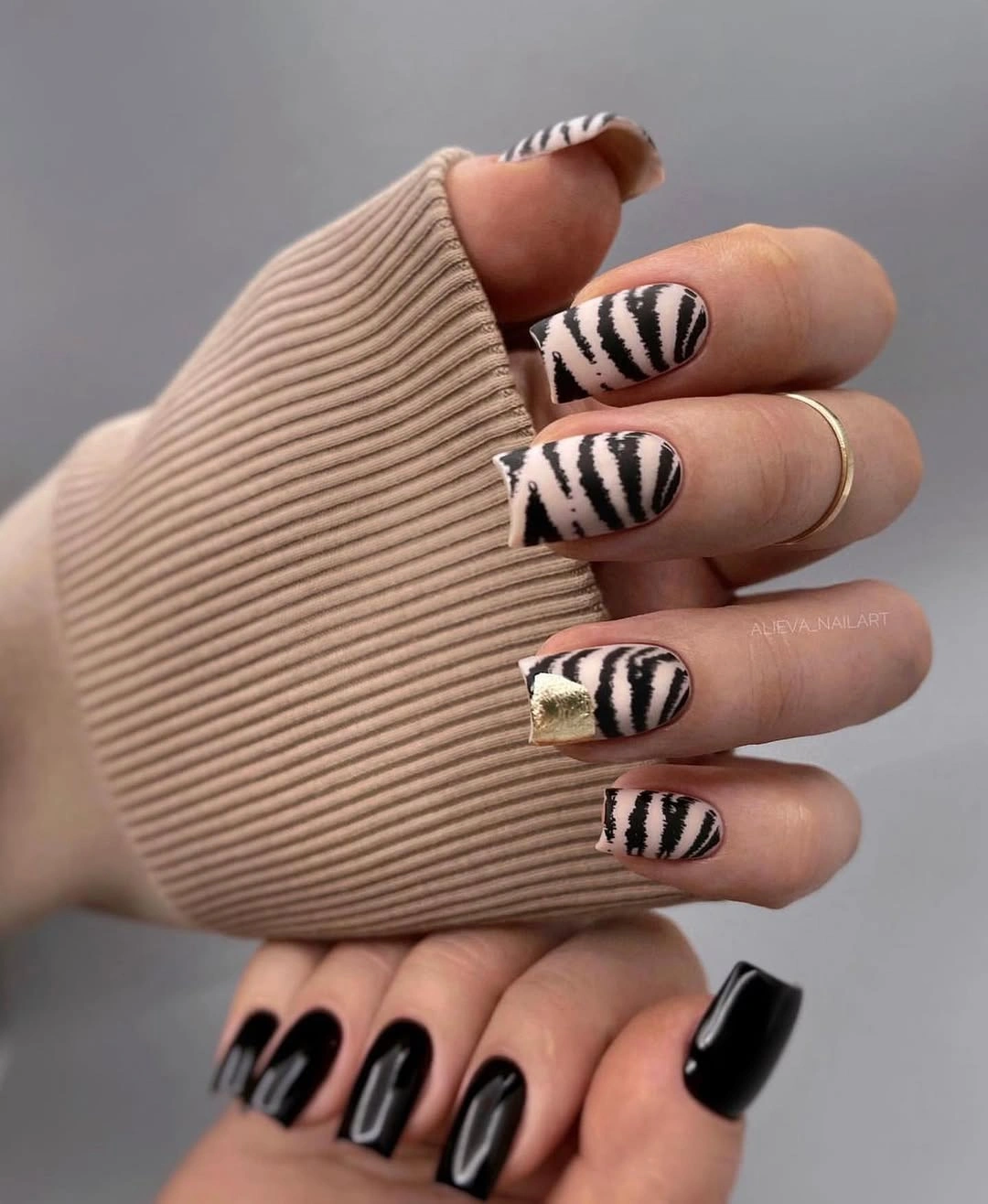 Short black square nails with zebra striped accents and a gold block