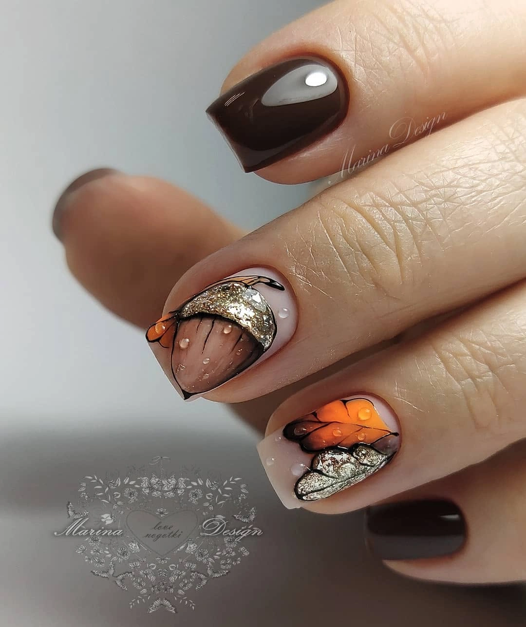 Short brown square nails with silver glitter arcs and orange accents