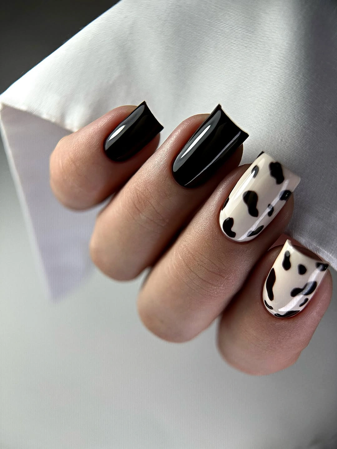 Medium glossy black square nails with two cream cow print accents