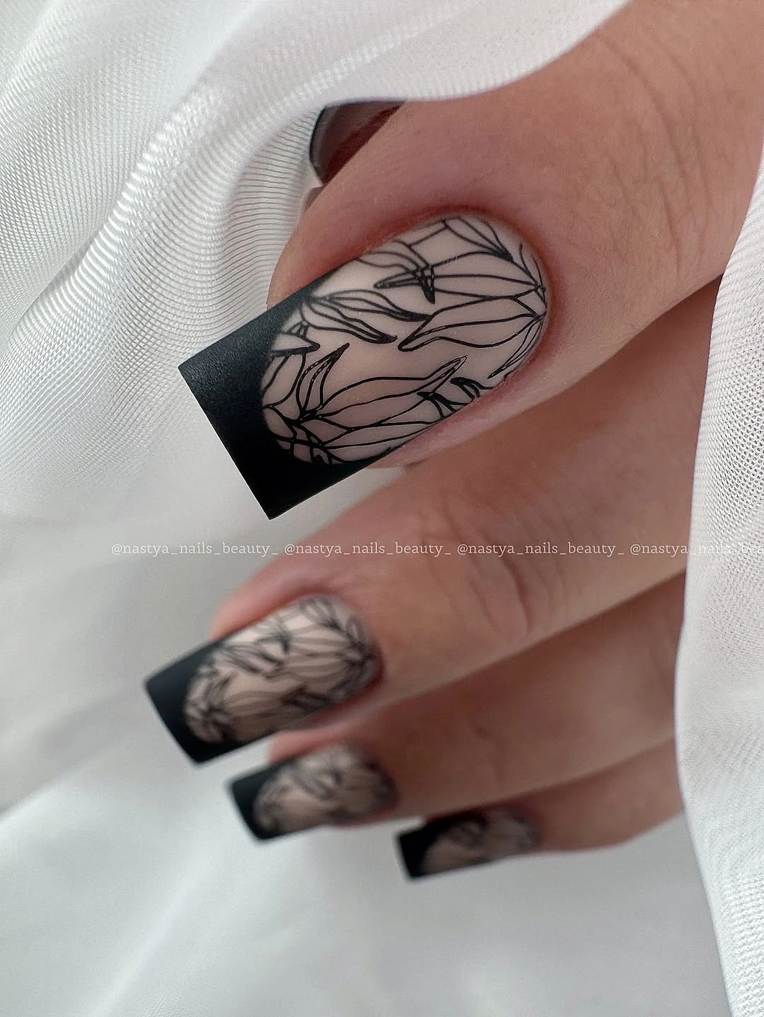 Long taupe square nails with black tips and botanical linework