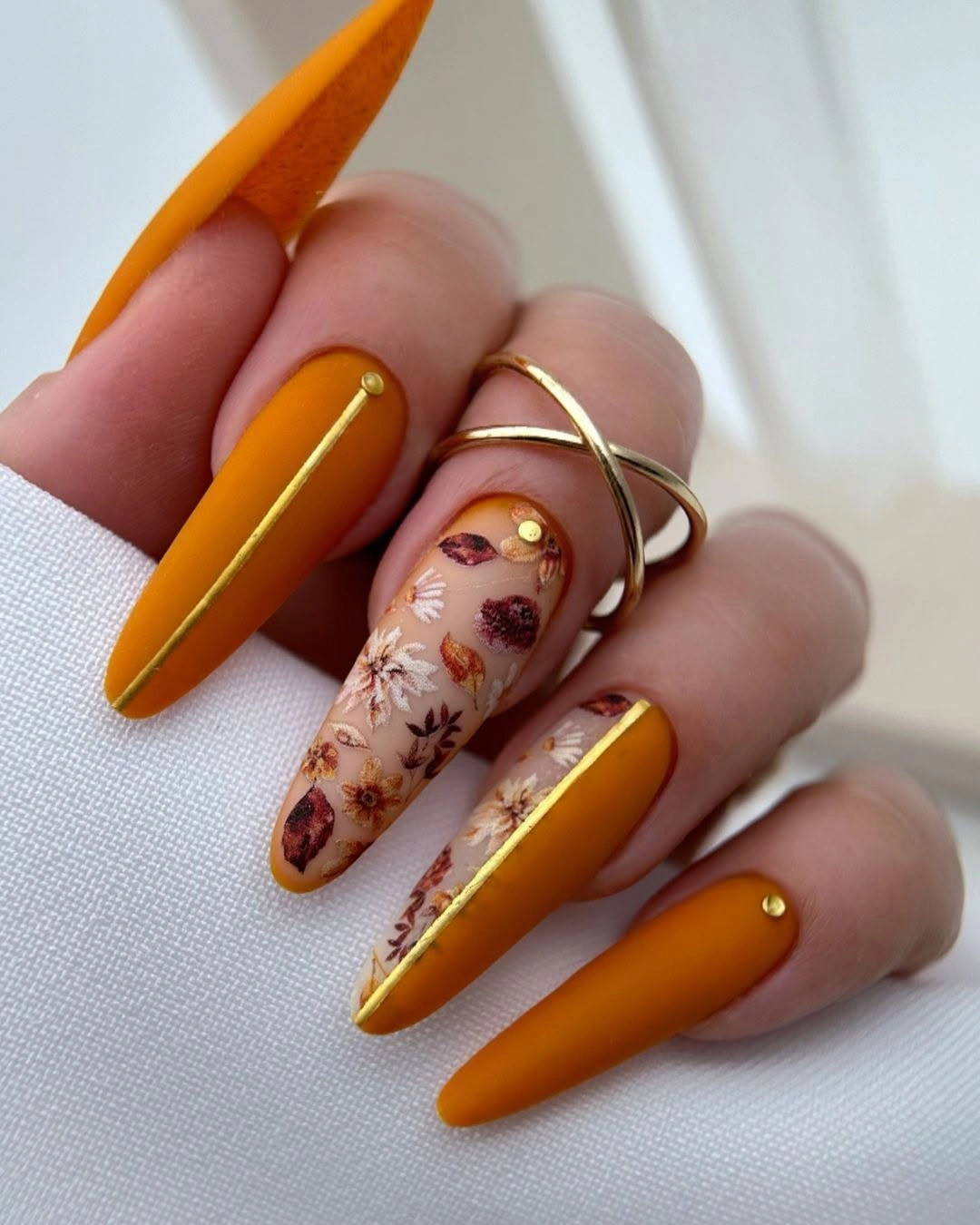 Long orange stiletto nails with one pale floral seasonal accent