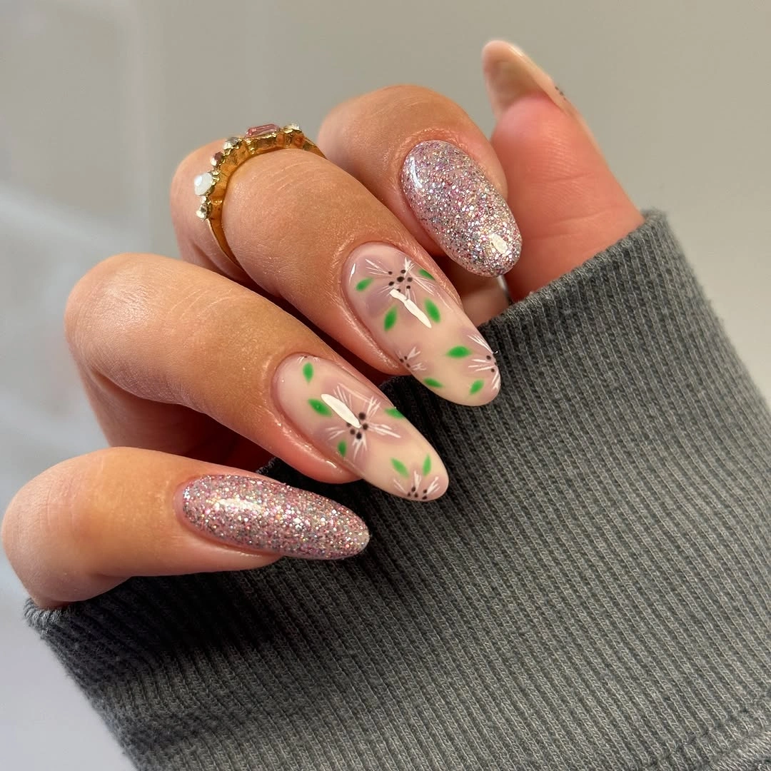 Nude almond nails with green sprigs and rose gold glitter accent