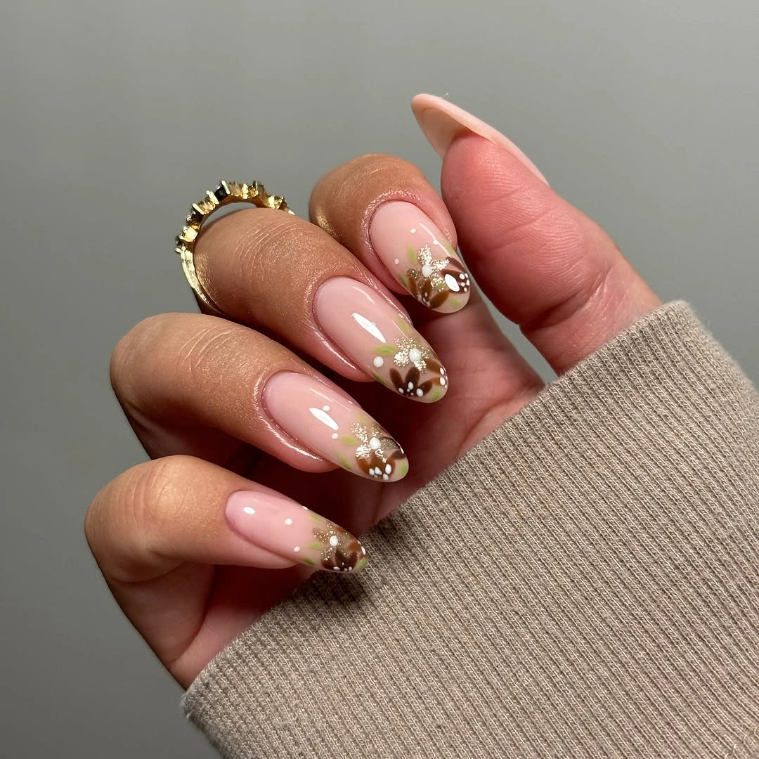 Nude almond nails with brown marbled tips and gold leaf accents