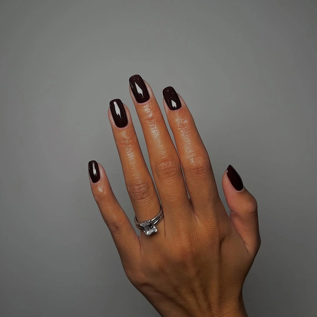 Short rounded nails in glossy deep oxblood brown