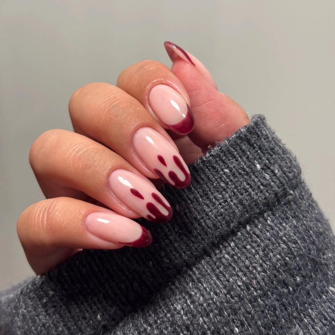 Nude almond nails with flowing glossy burgundy reverse tip waves