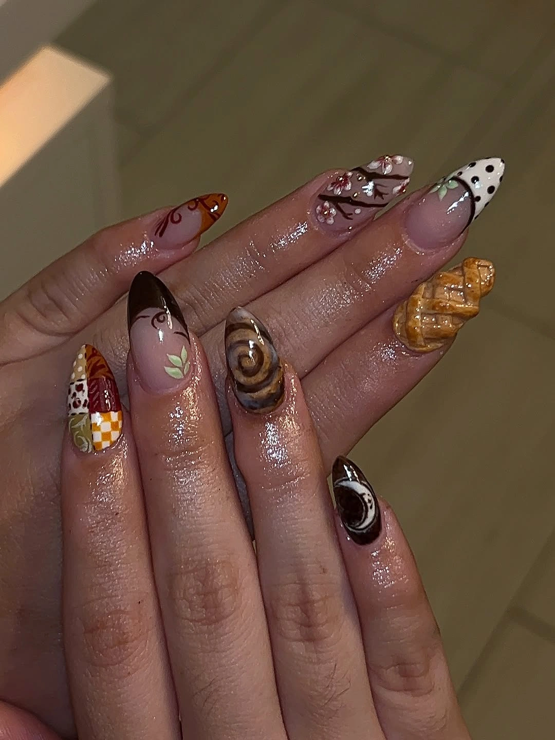 Long pointed nails with brown burgundy dots sprigs and charms
