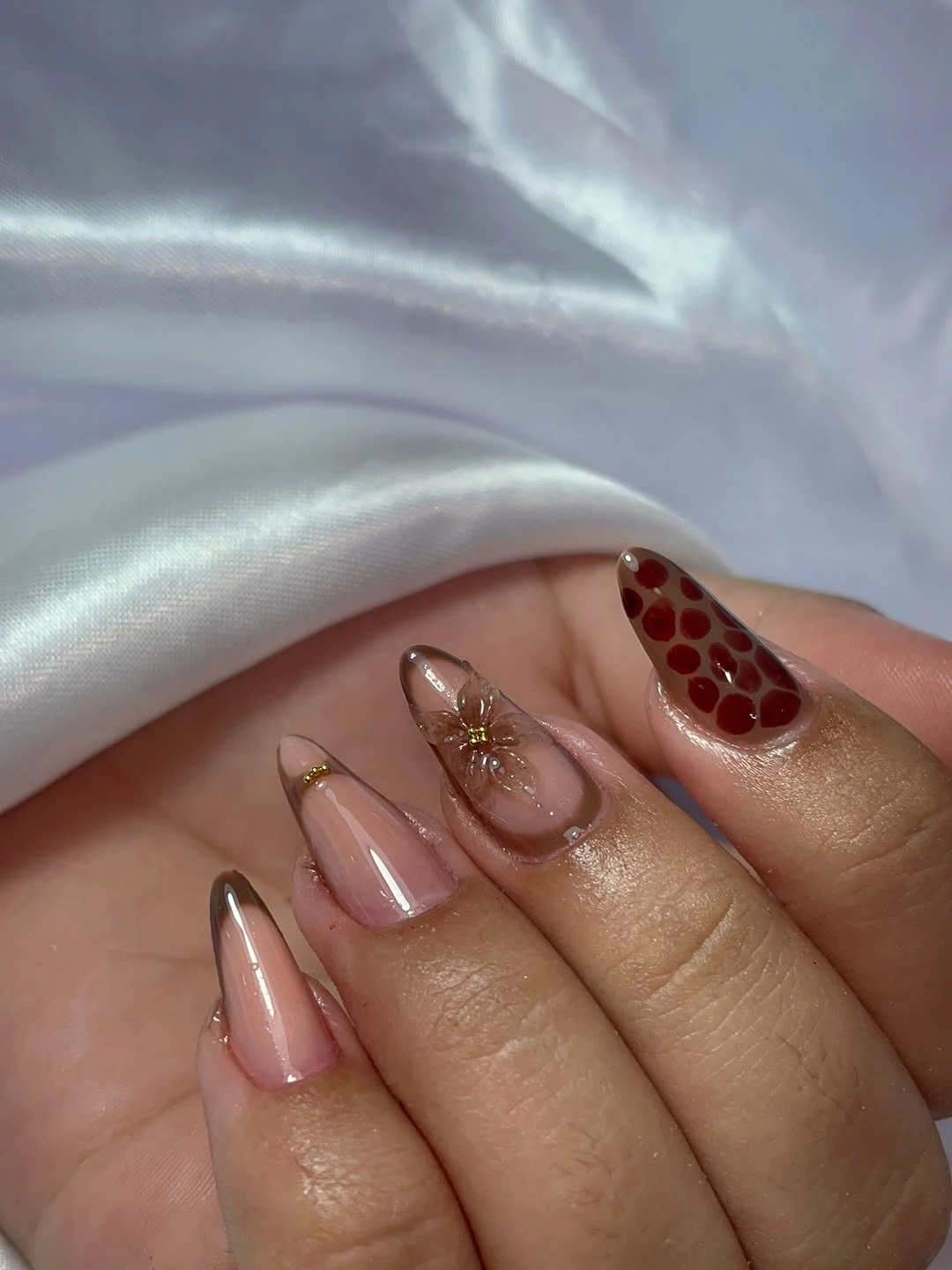 Sheer almond nails with brown outlines red dots and gold accent
