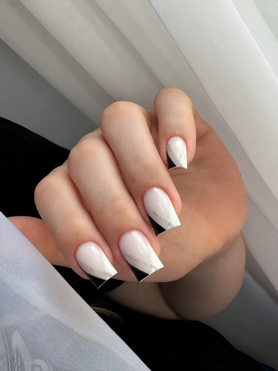 White pointed nails with black geometric French corners and flecks