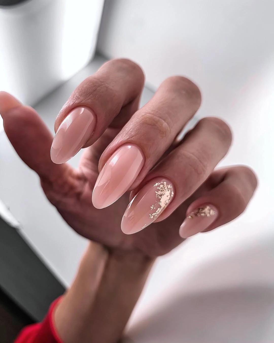 Blush almond nails with irregular gold foil and pearly accents