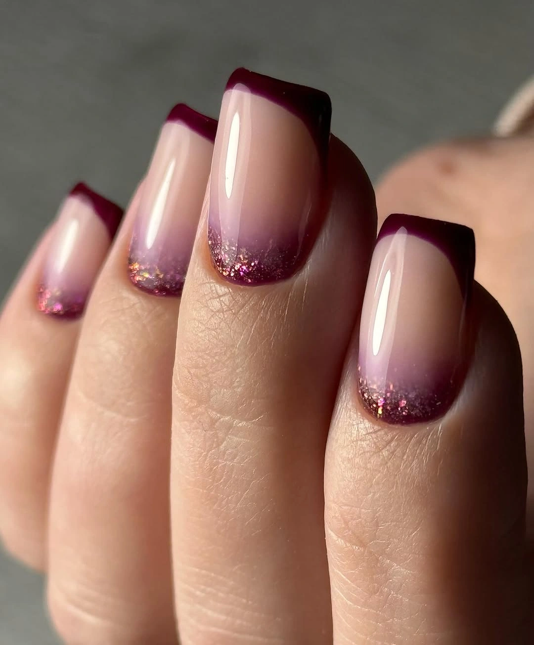 Square nude nails with deep burgundy frames and subtle pink sparkle