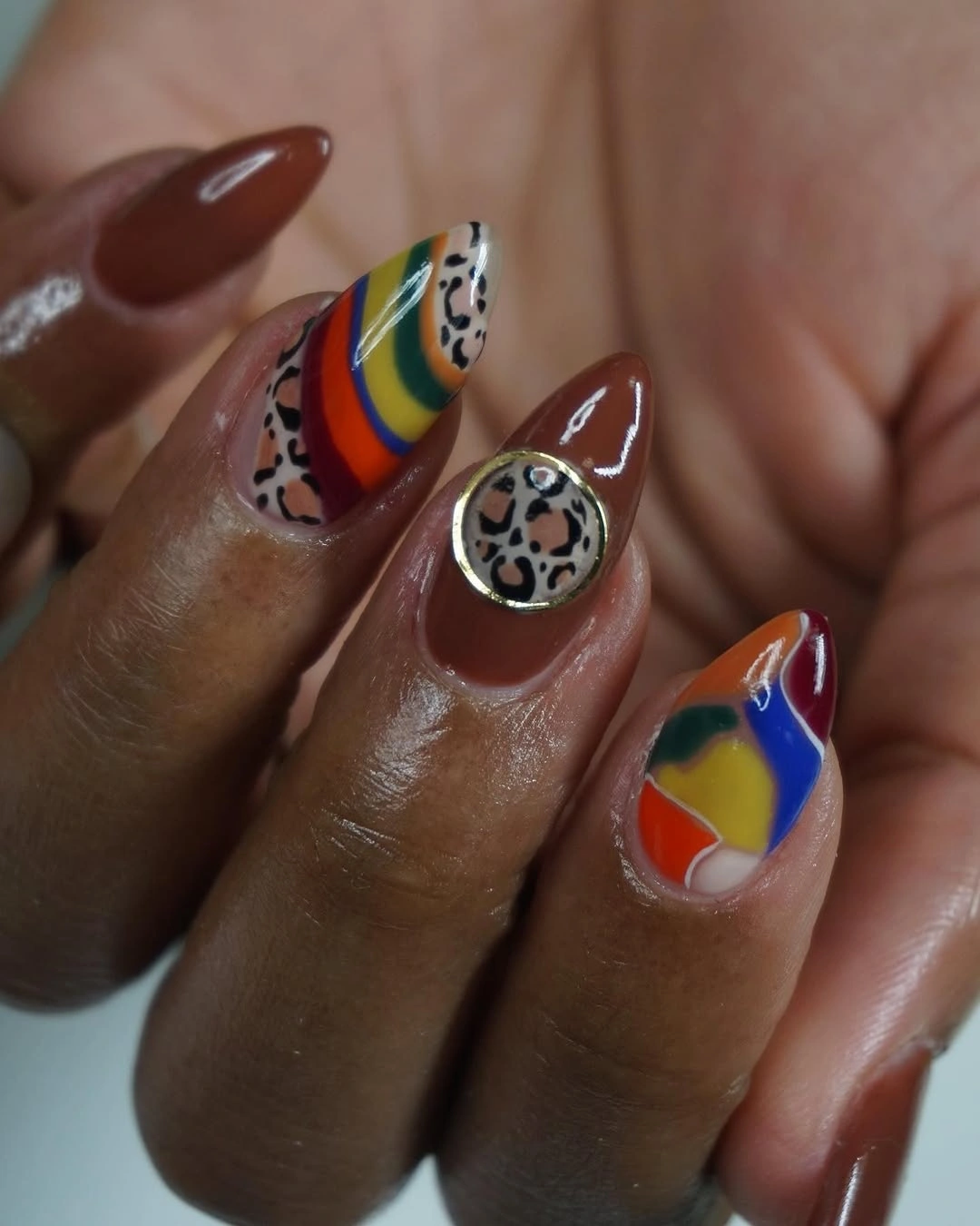 Long brown almond nails with multicolor bands and animal print accents