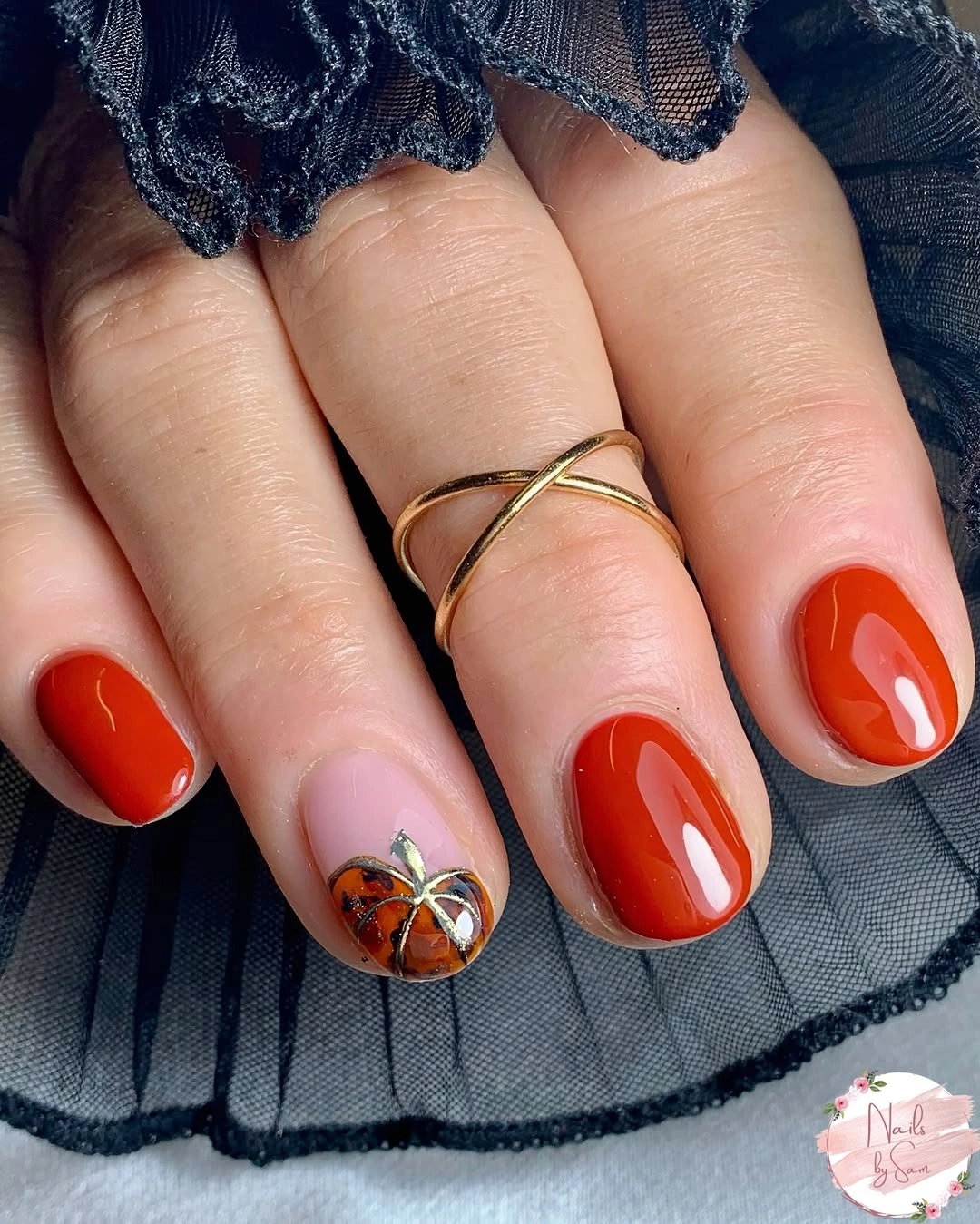 Short glossy red nails with one pale seasonal floral accent