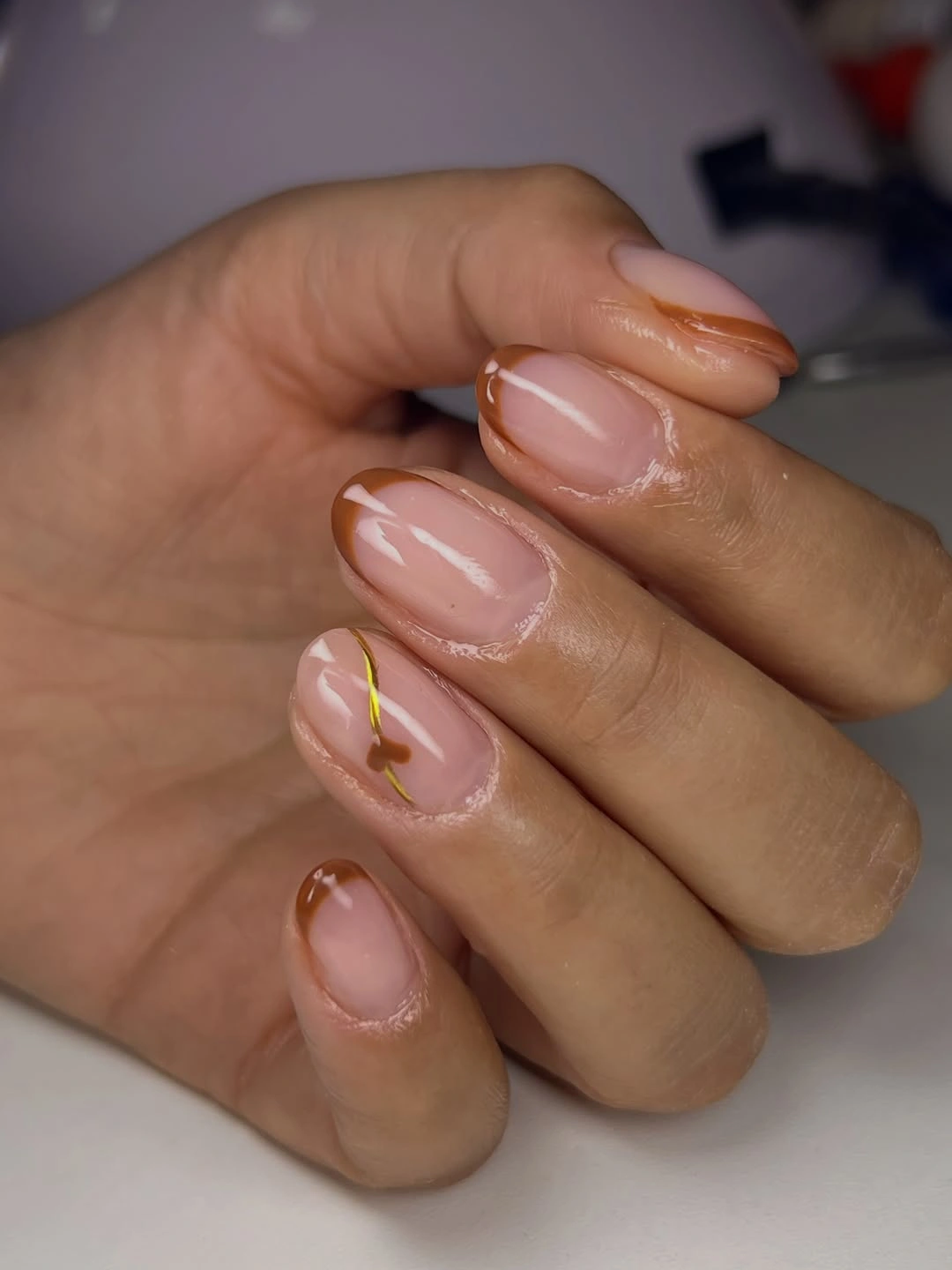 Short sheer nude oval nails with sparse brown white and gold lines