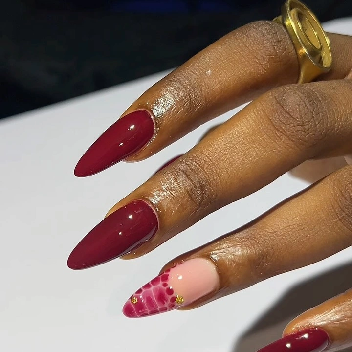 Long burgundy almond nails with one pink spotted accent nail