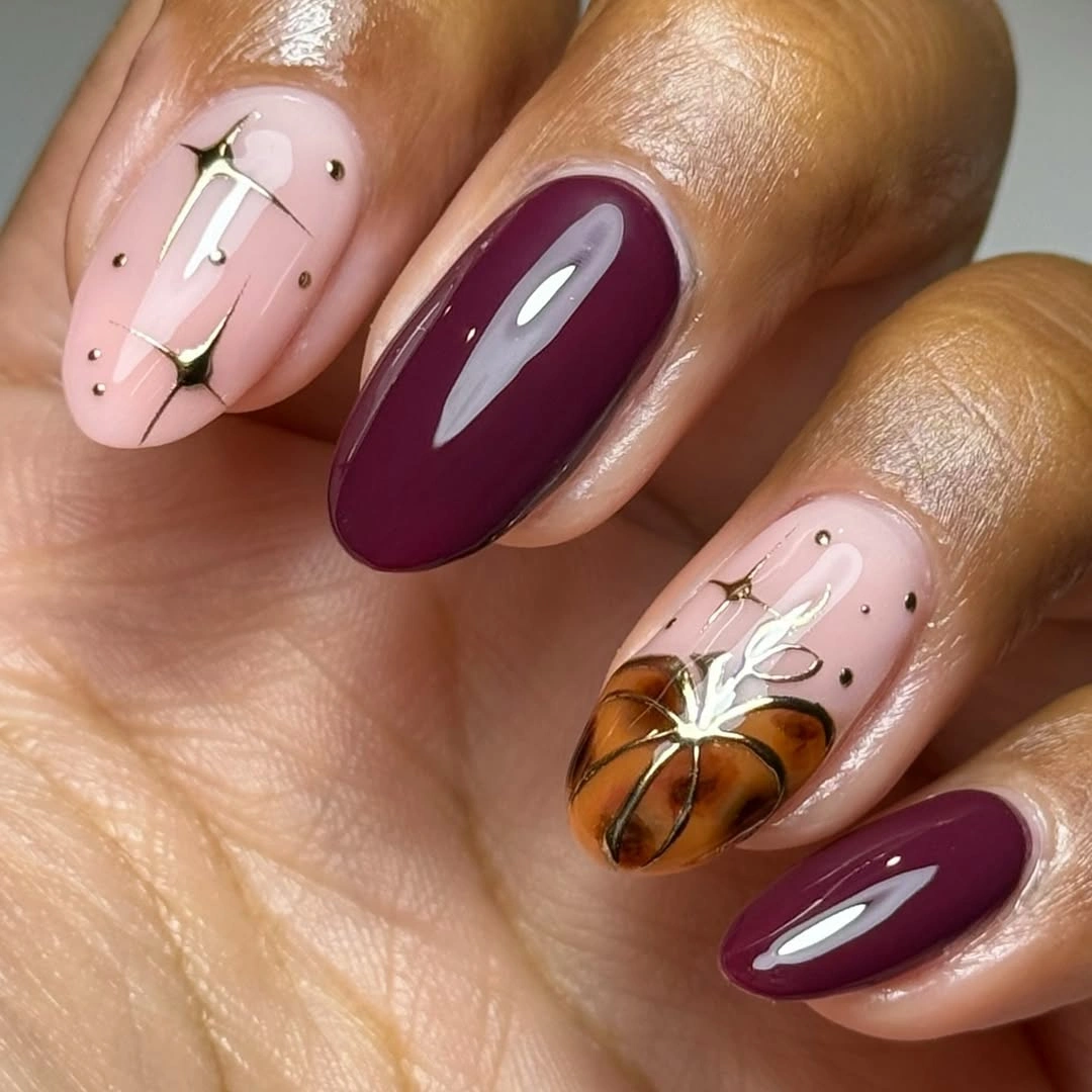 Medium nude oval nails with burgundy and a pumpkin accent