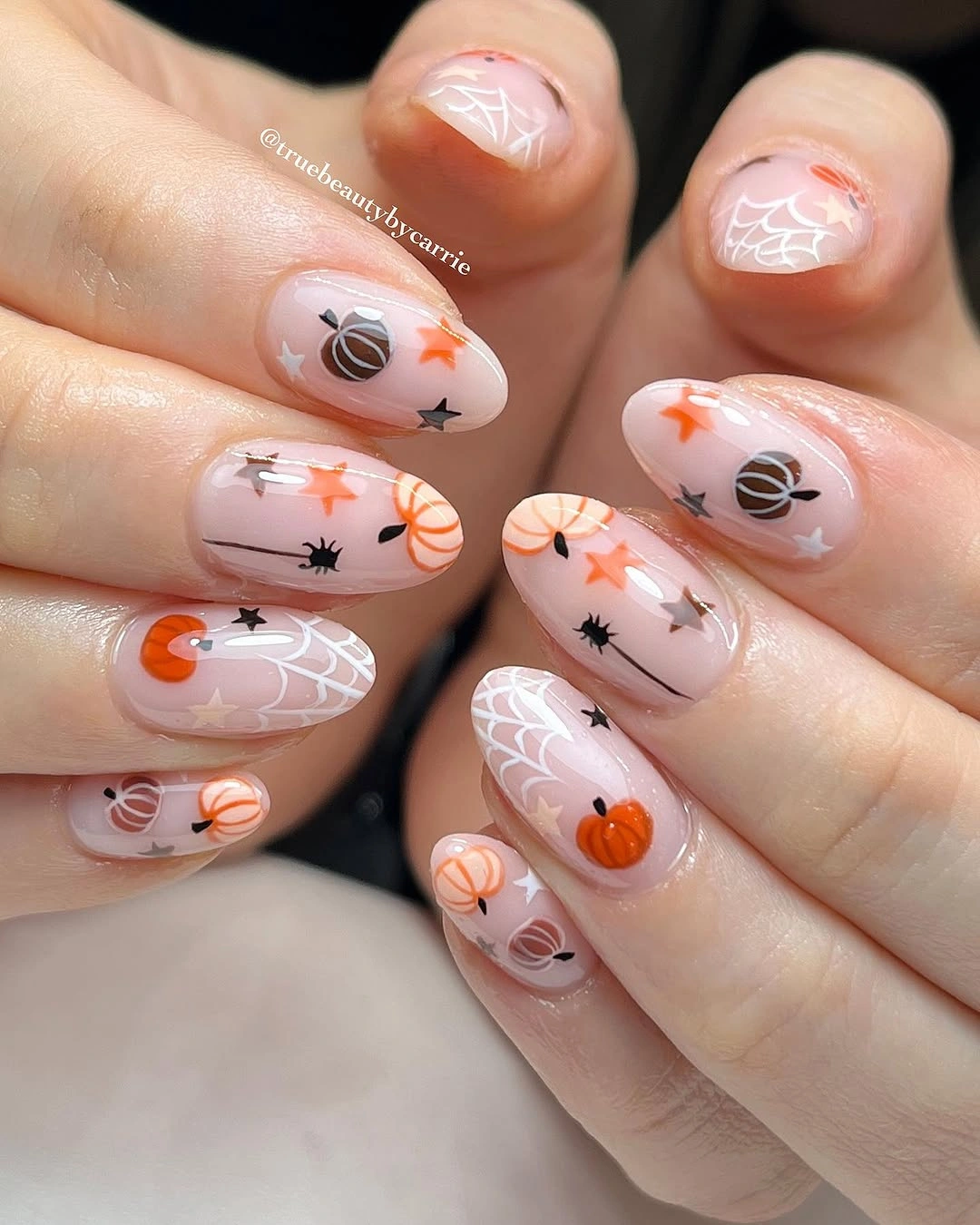 Short nude pink nails with miniature orange pumpkins and delicate seasonal marks