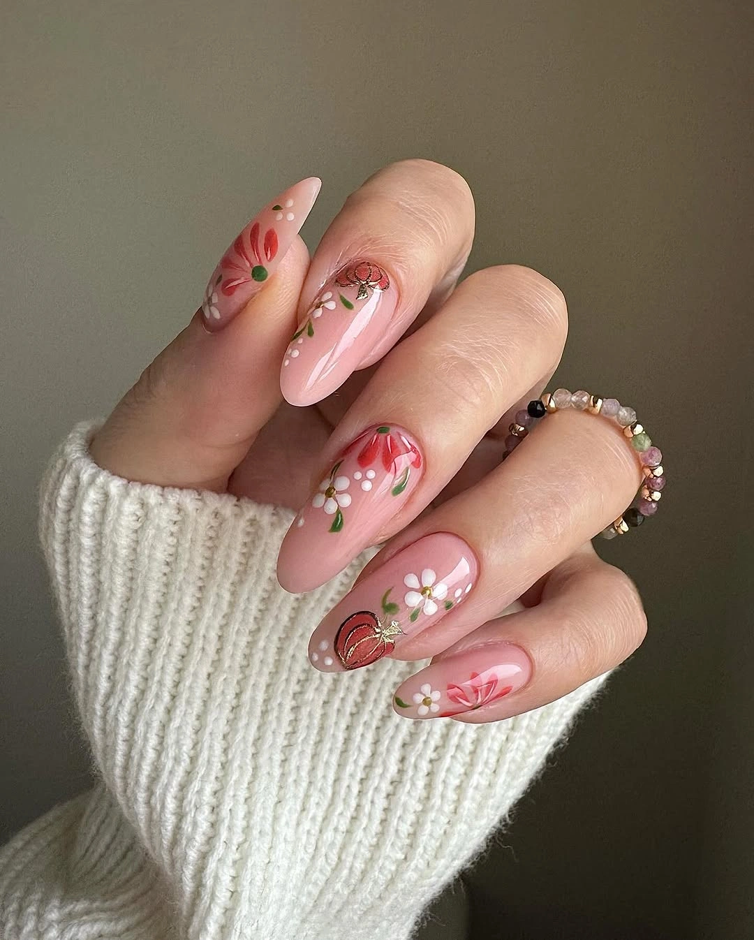 Blush pink almond nails with small warm red seasonal accents