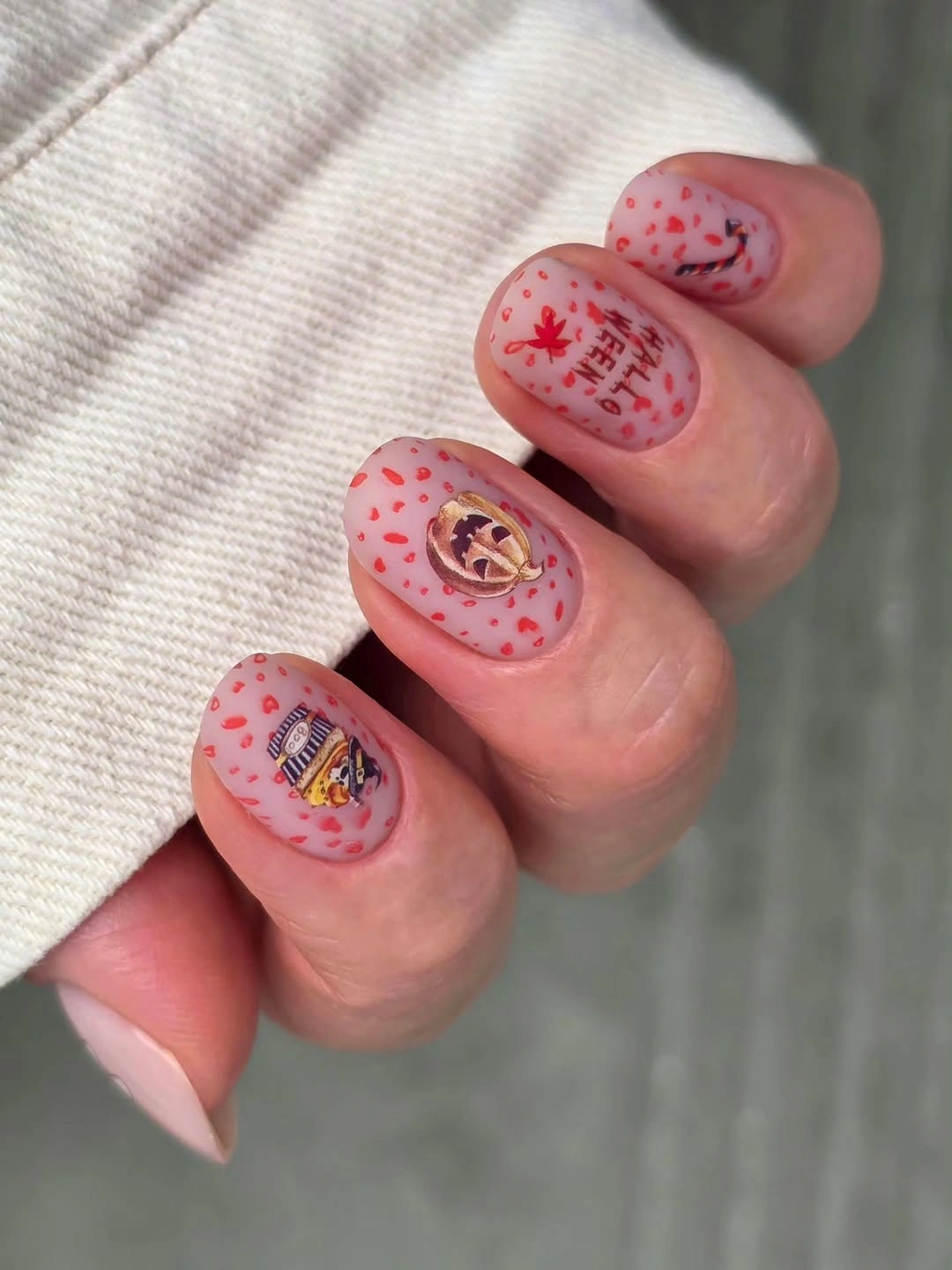 Short glossy rosy nails with repeated miniature fall and Halloween motifs