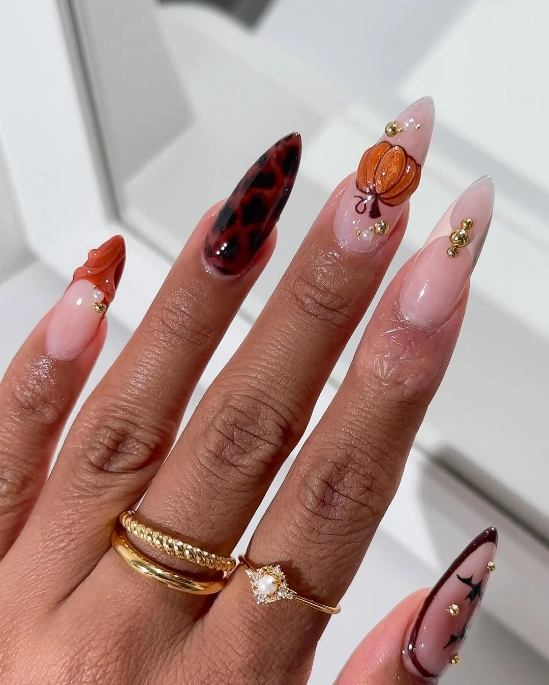 Long pink stiletto nails with one dark marbled accent and orange detail