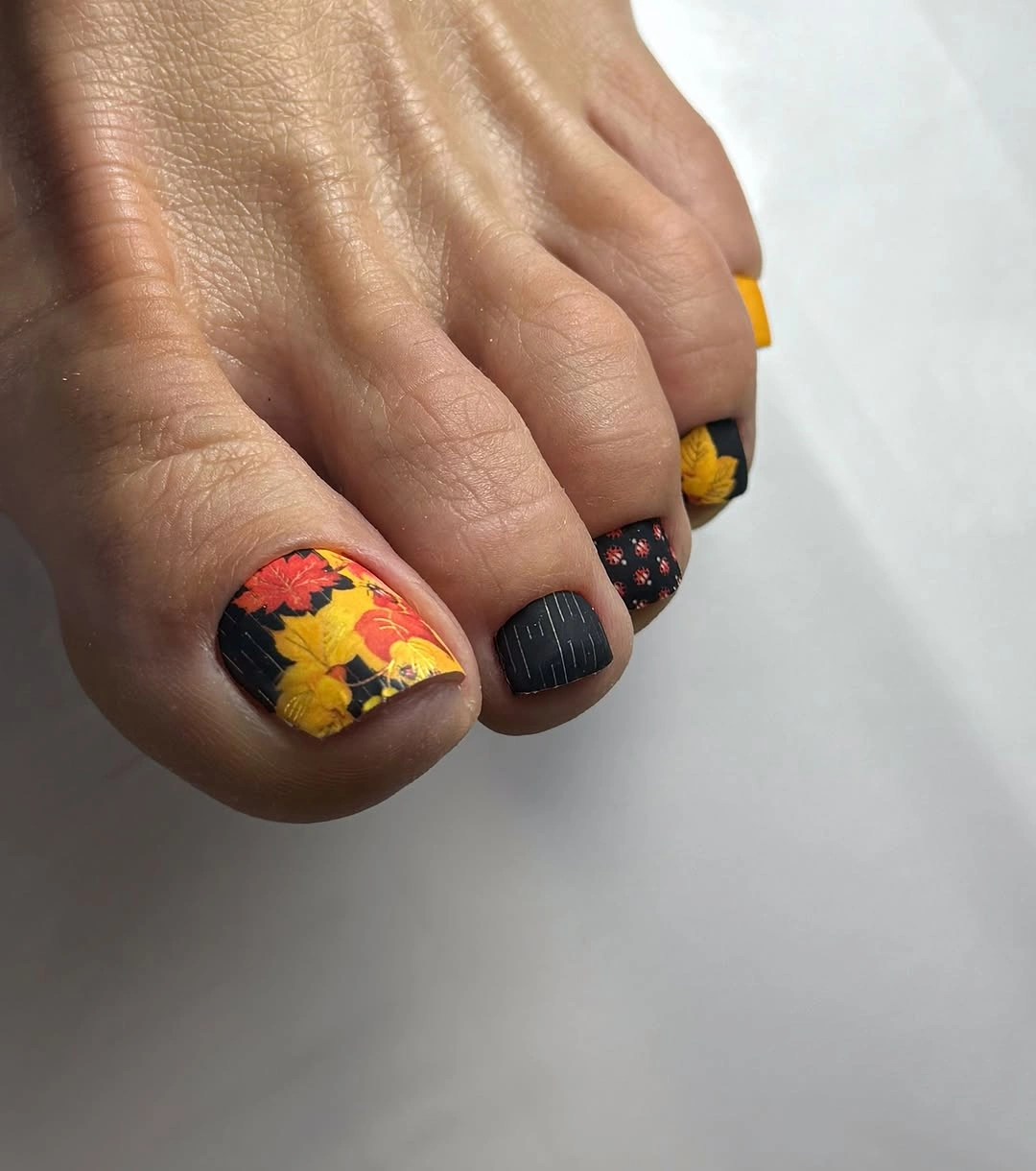 Autumn leaf pedicure with black and yellow accents
