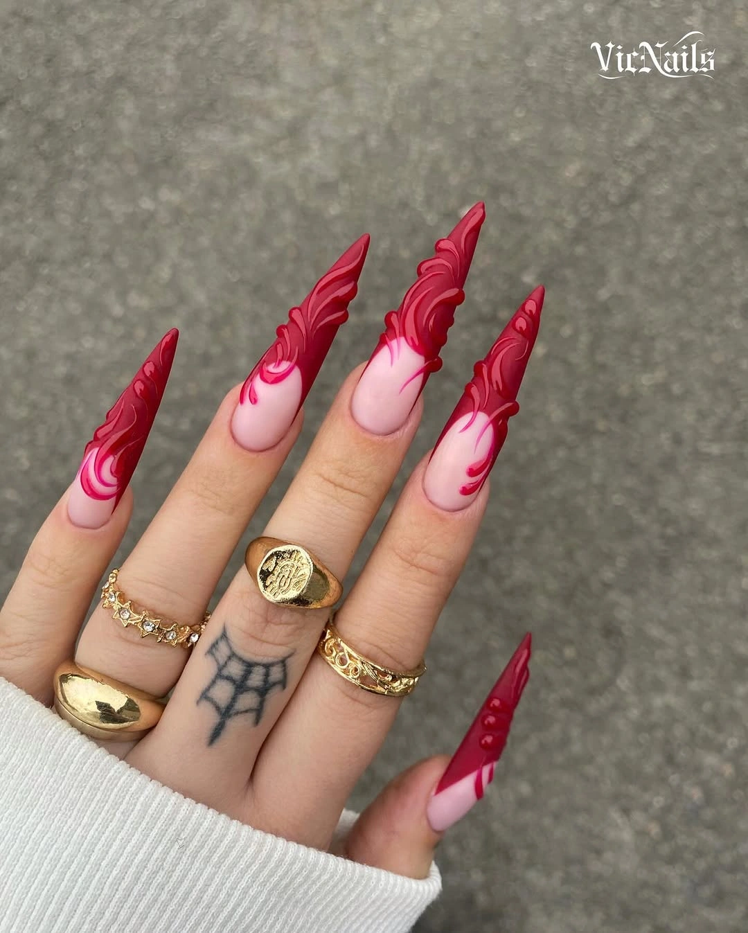 Pale stiletto nails with sculptural red swirls