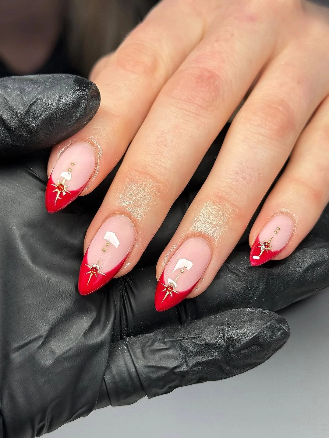 Short almond red tips with gold starbursts