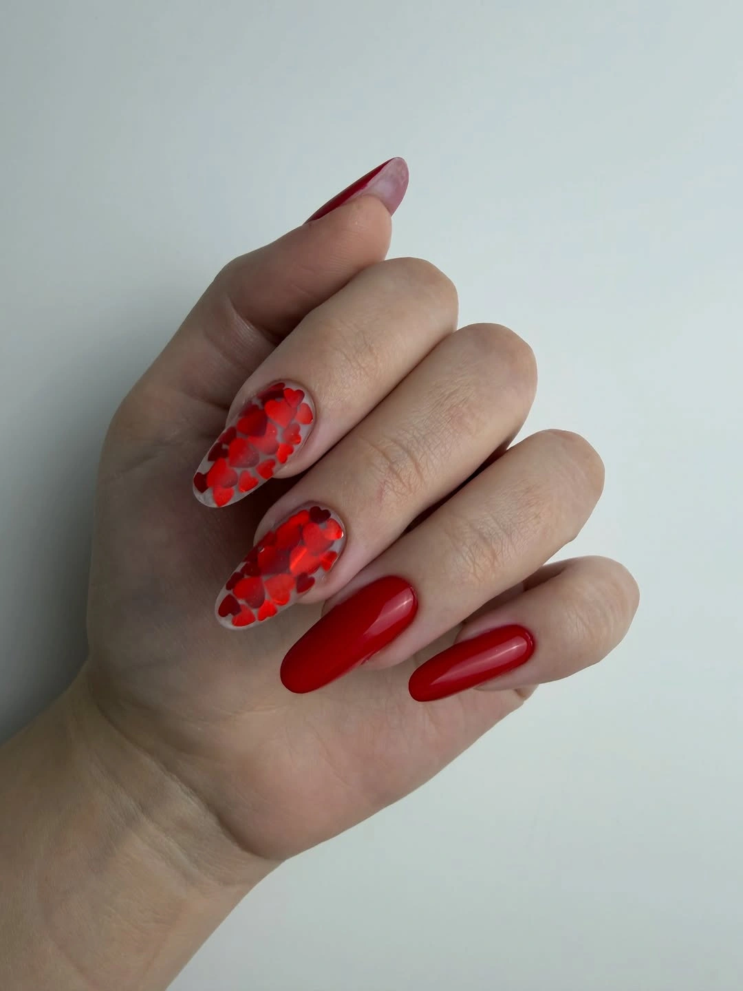 Red almond nails with layered heart accents