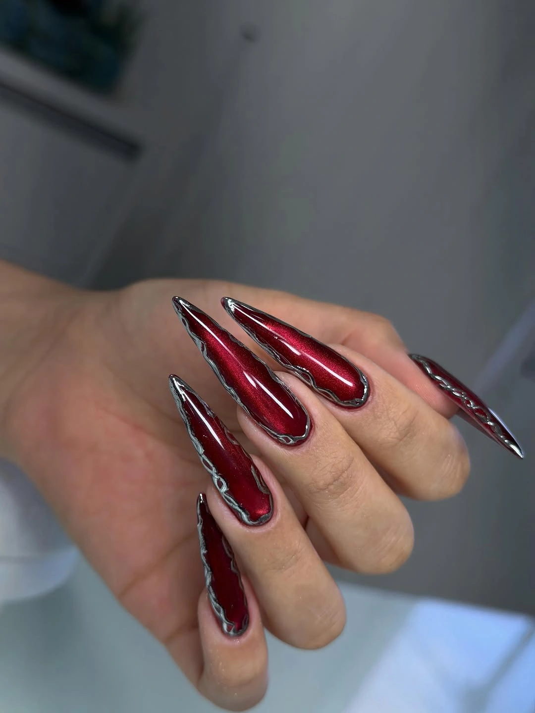 Metallic burgundy stiletto nails with silver waves