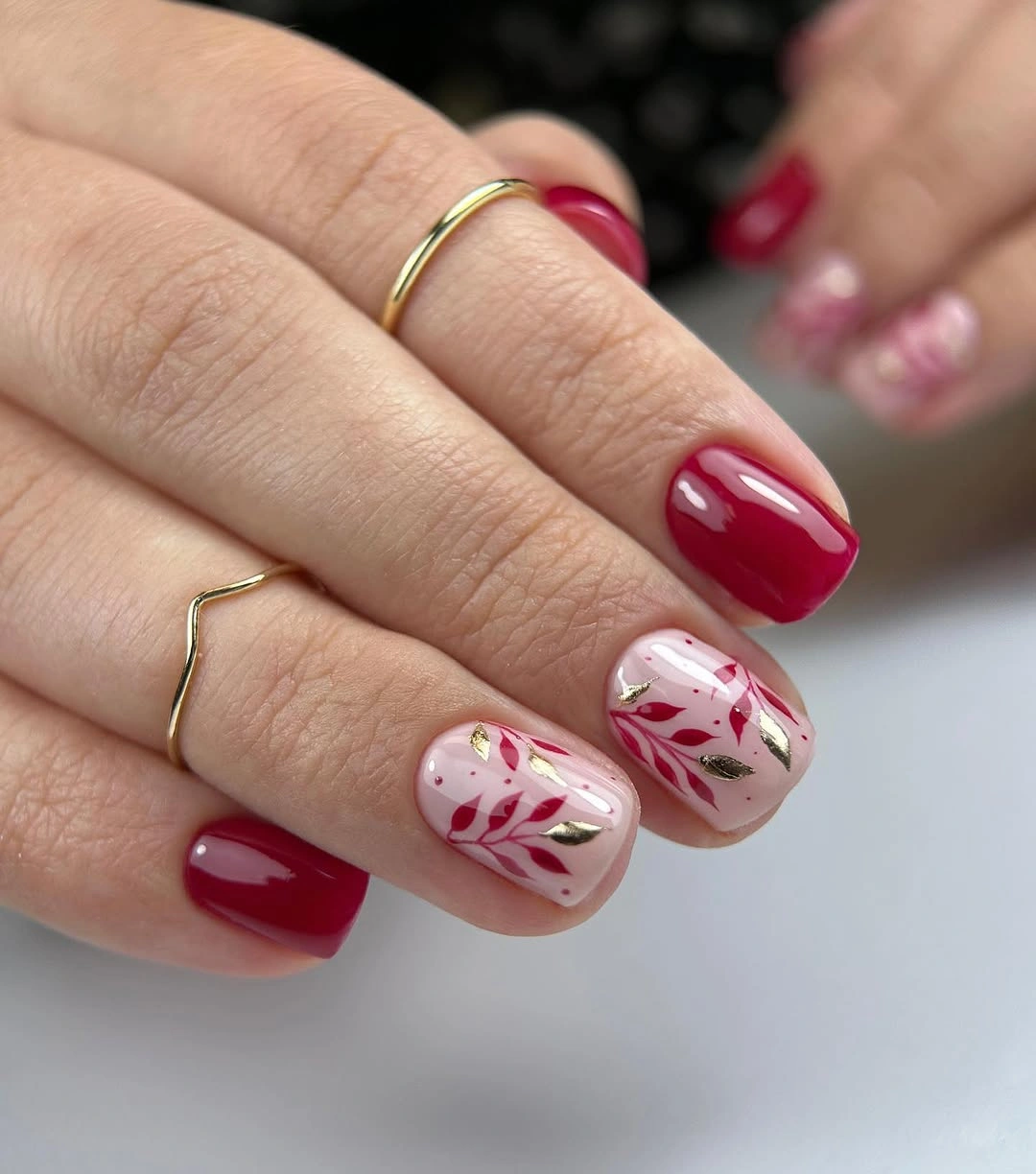 Short red square nails with pale botanical accents