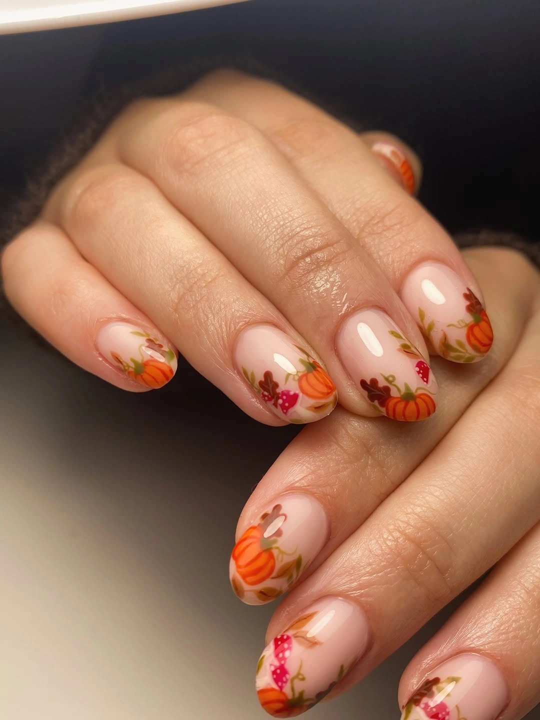 Short-to-medium almond nails with sheer nude bases and tiny orange-red marks